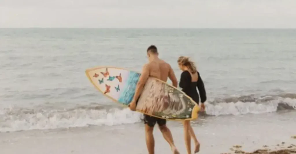beach couple poses with surfboard