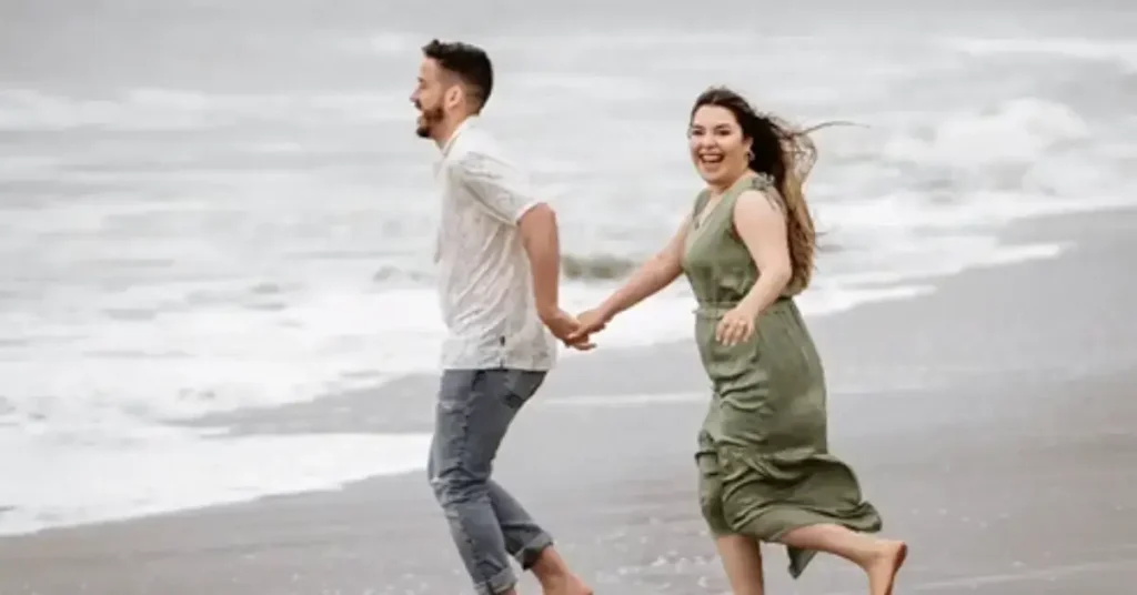 beach couple poses running hand in hand