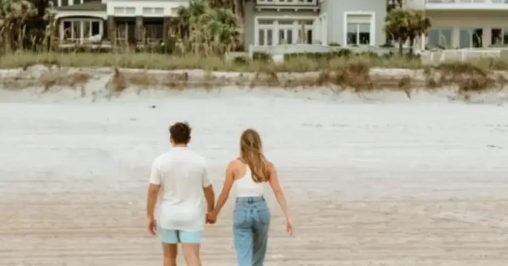 beach couple poses walking hand in hand