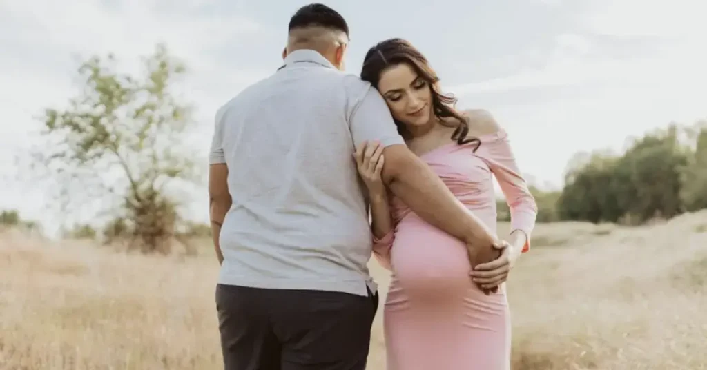 couple maternity poses hand on the belly of the woman in the pink dress