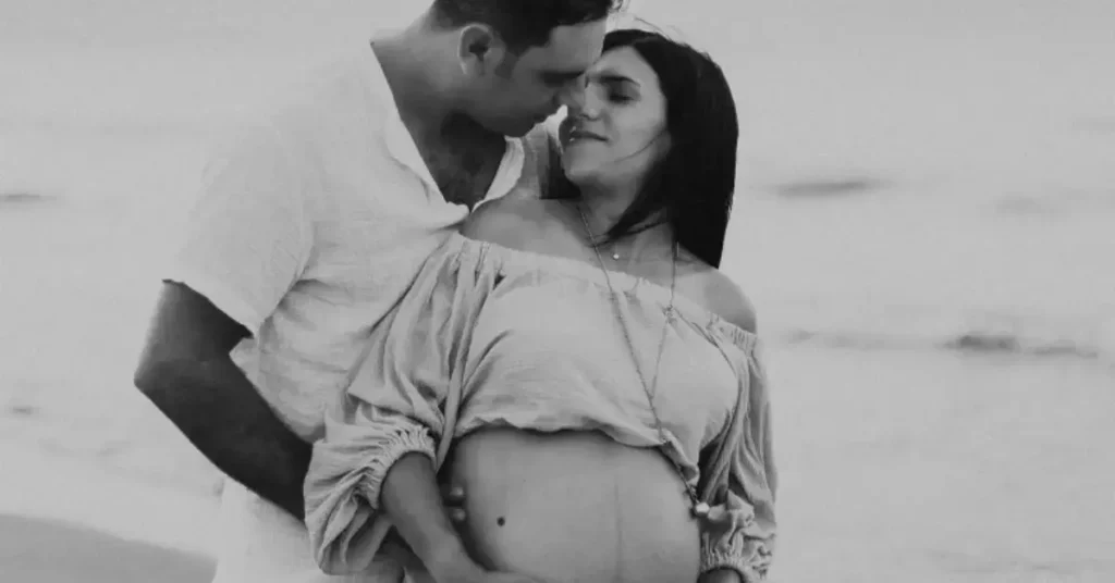 couple maternity poses outside in front of the water