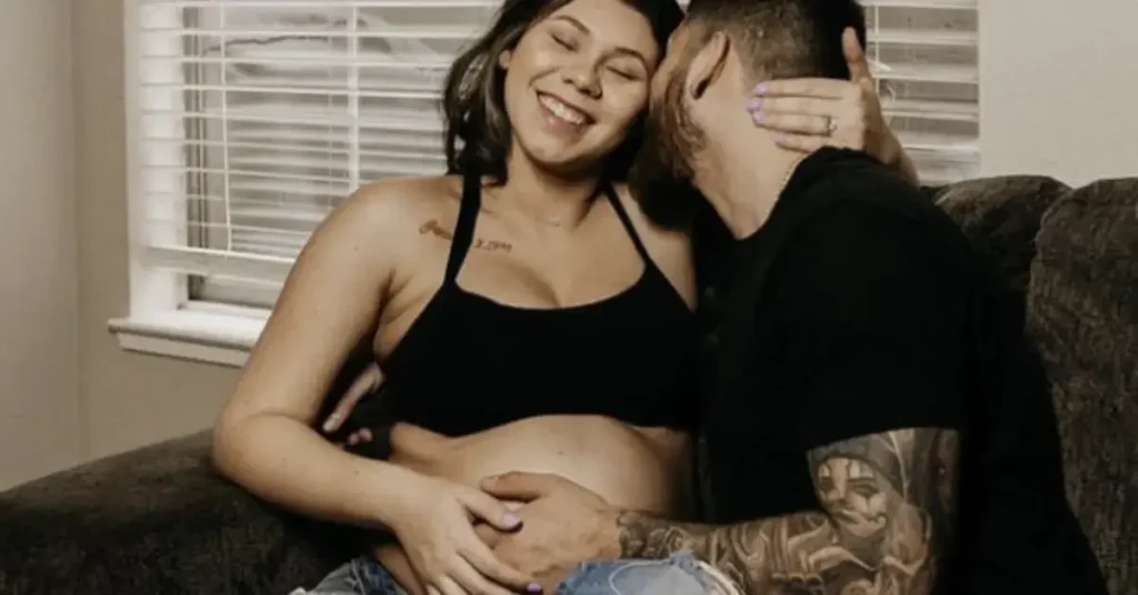 couple maternity poses hand on the belly laughing