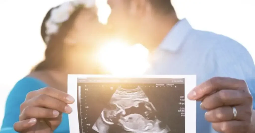 couple maternity poses kissing with ultrasound photo